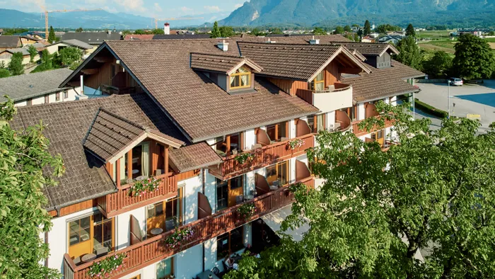 Traditionelles Alpenhotel mit Blumenbalkonen und Bergblick im Sommer